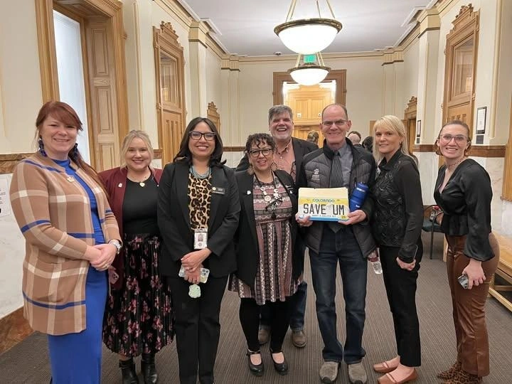 Executive Director Doug Rae and staff from the Humane Society of Fremont County standing together at the Colorado State Capitol, celebrating progress on HB25-1137. The group is smiling, and one person is holding a Colorado license plate that reads 'SAVE UM.'